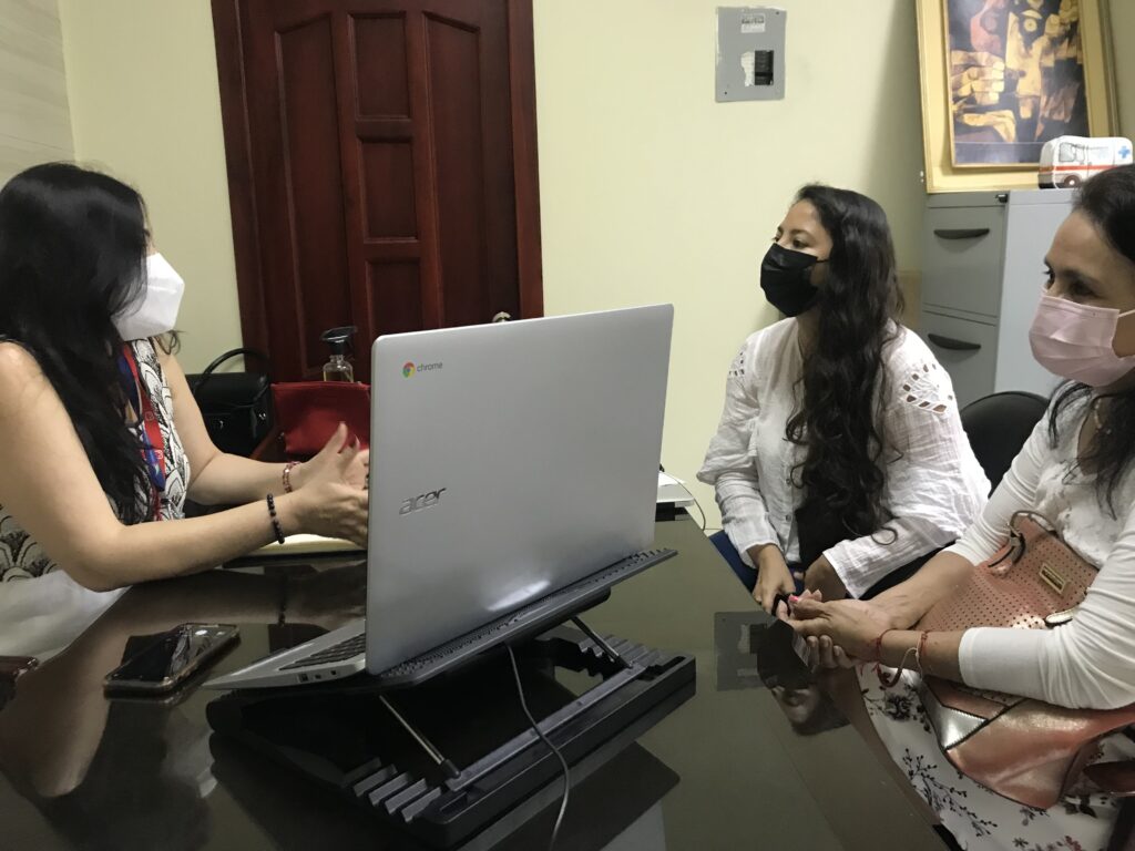 Participantes revisan información en una computadora durante una reunión.