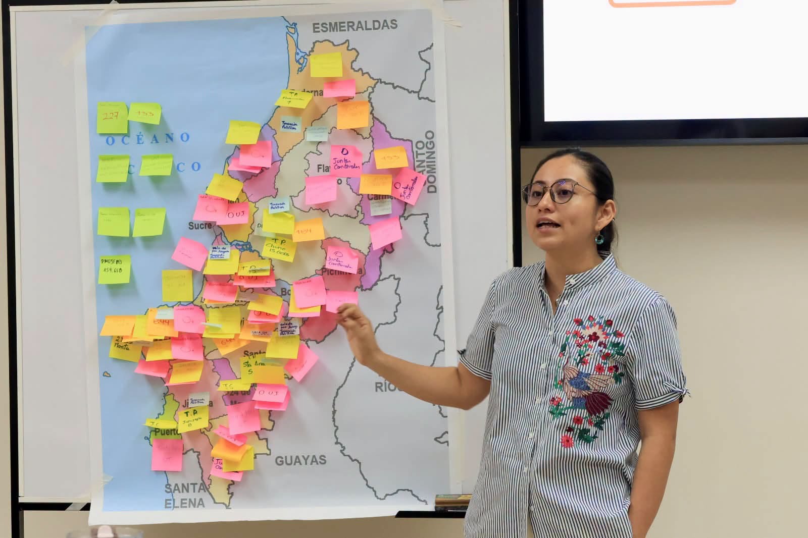 La facilitadora explica el mapa de Manabí cubierto con las notas de las personas participantes.